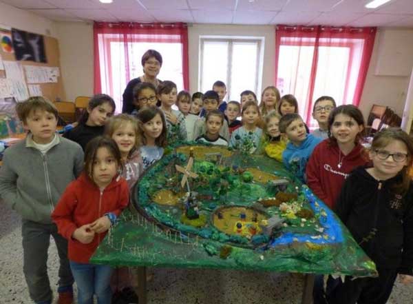 Groupe d'enfants avec leur enseignant réunis devant une maquette représentant l'éco système des étangs de la Dombes